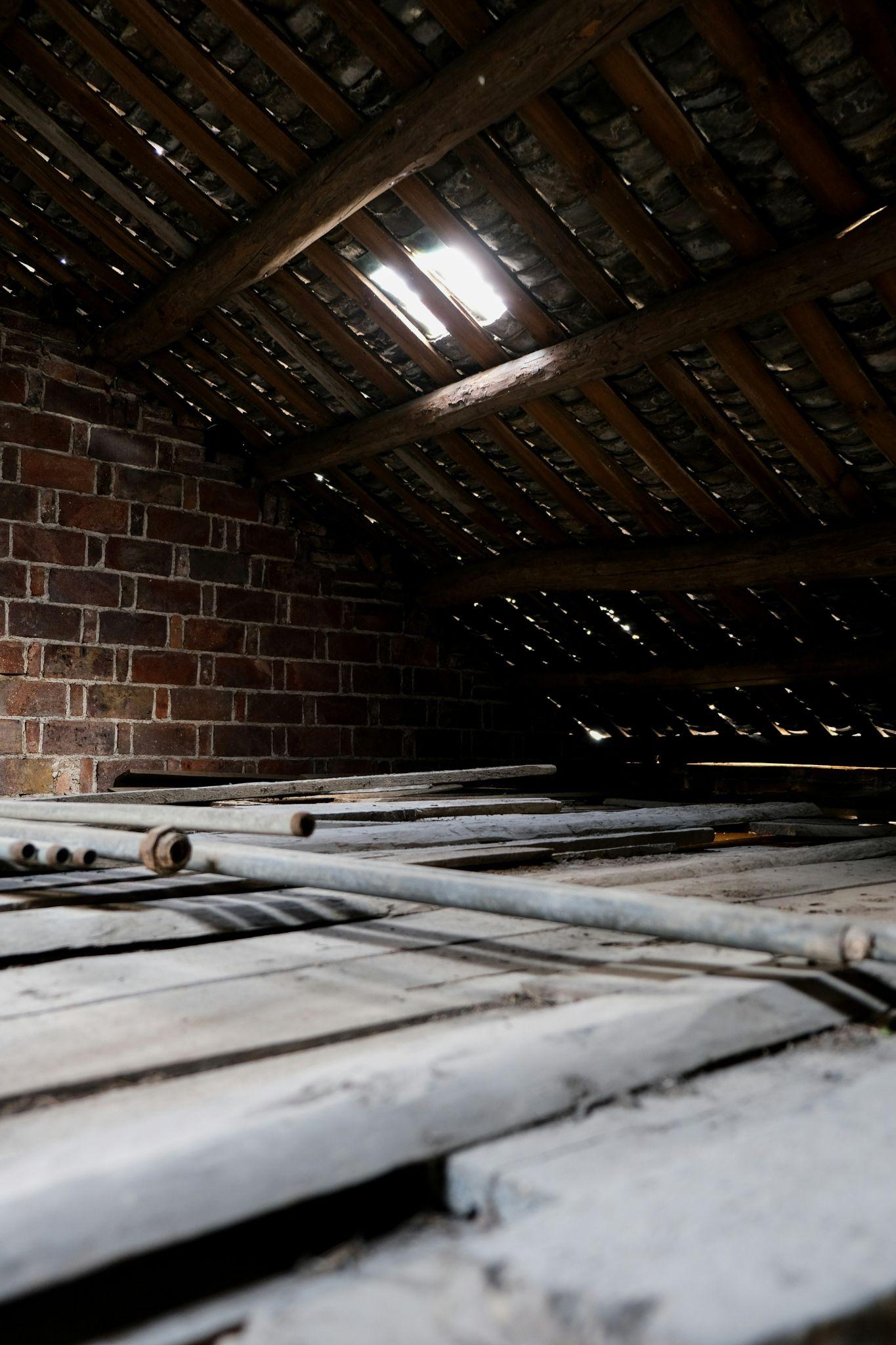 An older attic with exposed rafters and gaps in the roof shows a space suitable for attic insulation installation in Fresno.