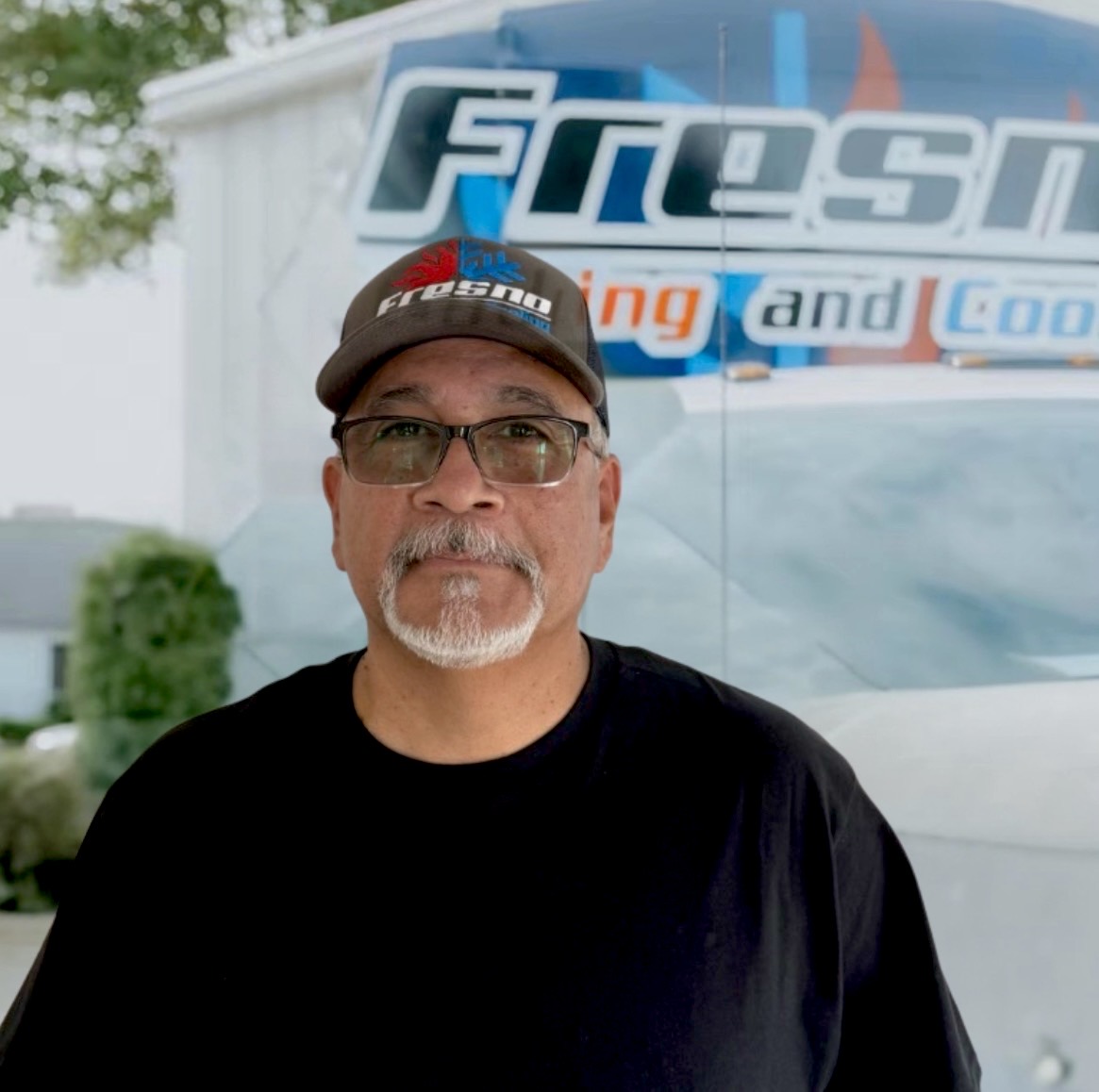 Tony Lopez Jr, shop lead at Fresno Heating and Cooling, standing in front of a company service truck
