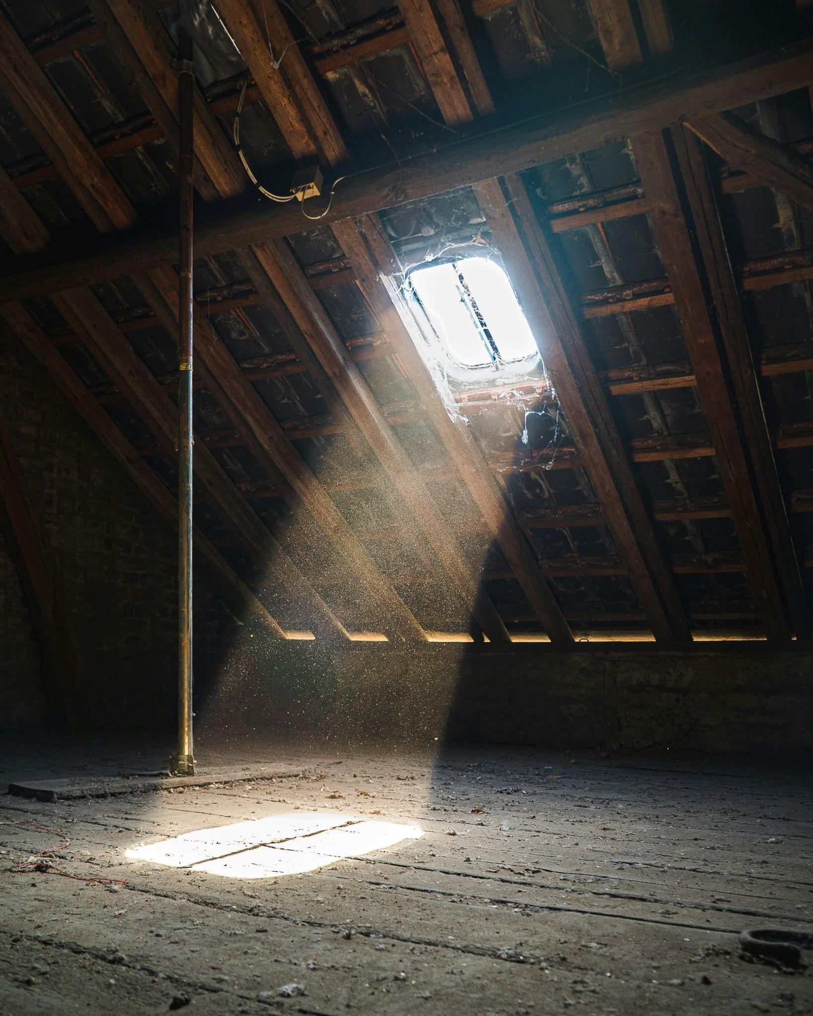 An attic with visible roof framing and debris illustrates an area that may require attic insulation removal in Fresno.