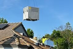 HVAC unit being lifted onto a rooftop by crane
