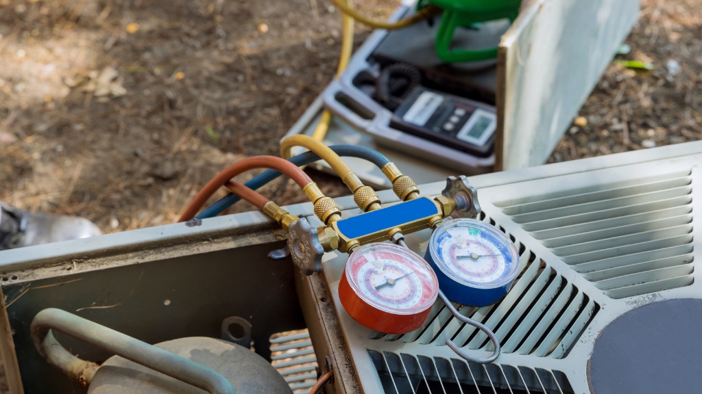 Technician testing refrigerant pressure gauges on a residential air conditioning system