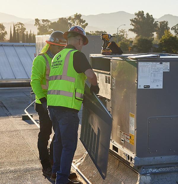 Technician inspecting a rooftop unit during commercial HVAC repair in California