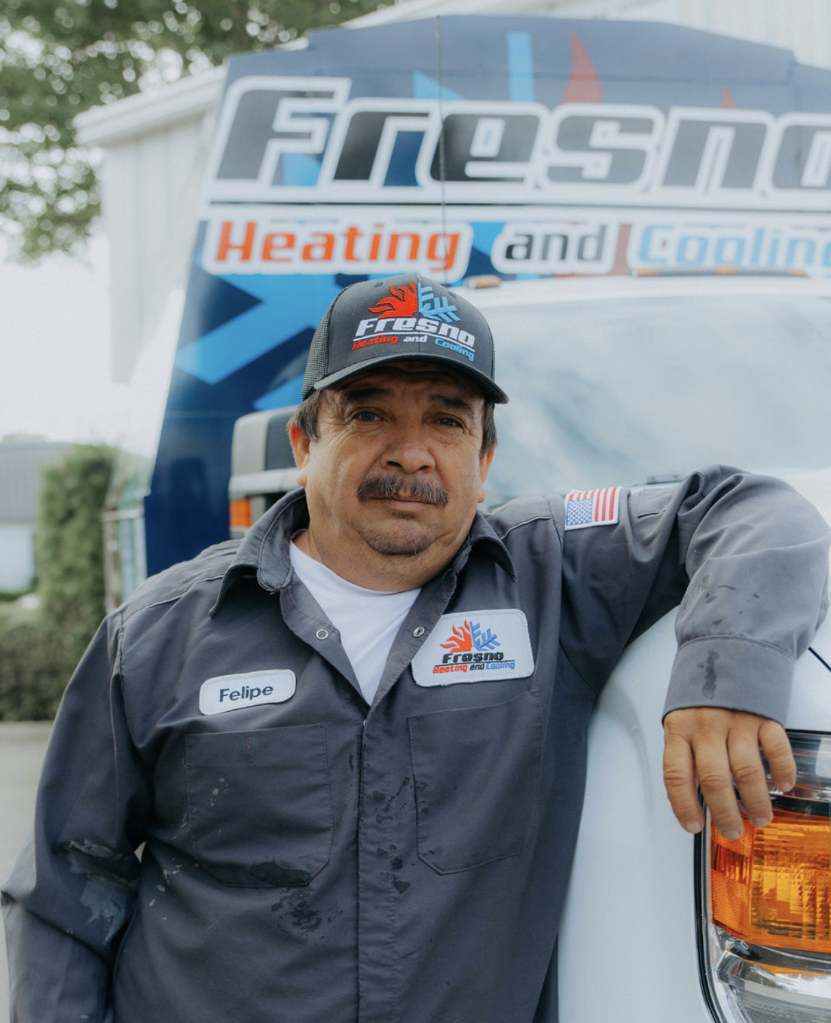 Felipe, install lead at Fresno Heating and Cooling, standing in front of a company service truck