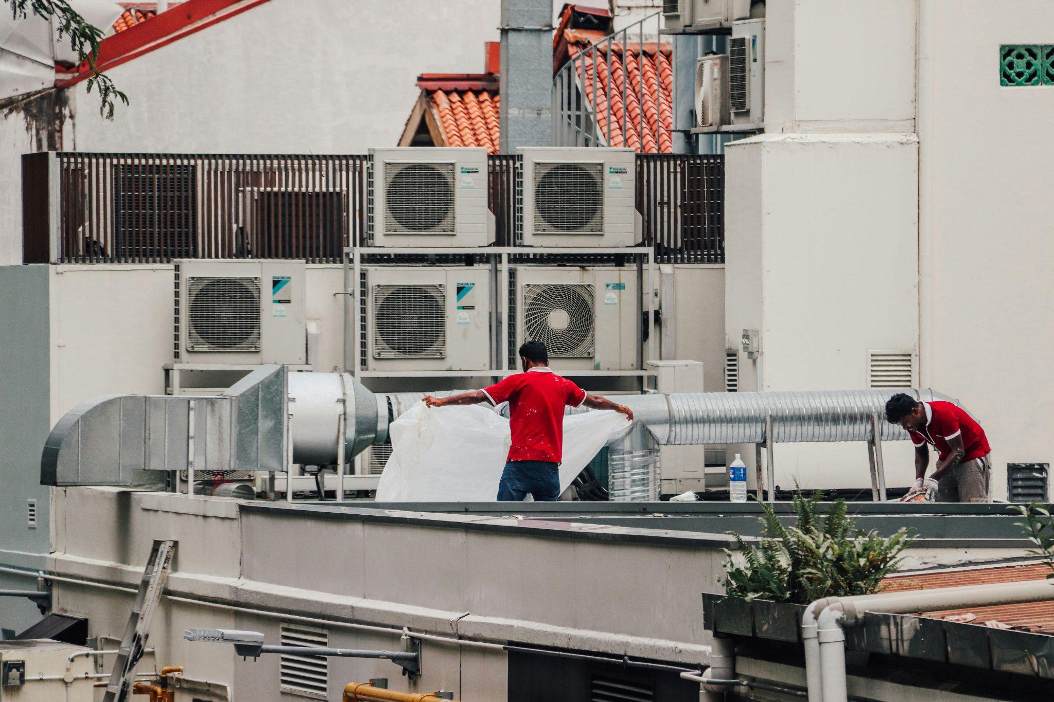 Technicians working on rooftop ventilation equipment highlight the importance of commercial HVAC maintenance in Fresno.