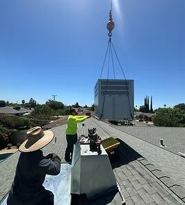 Technicians installing an HVAC unit on a roof in Fresno