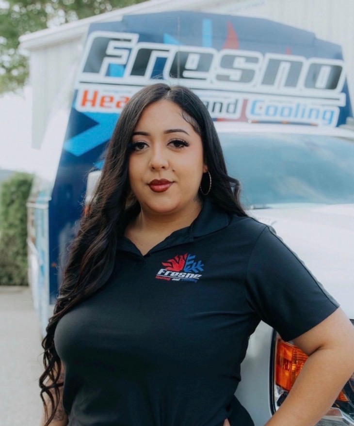 Luna, CSR at Fresno Heating and Cooling, standing in front of a company service truck