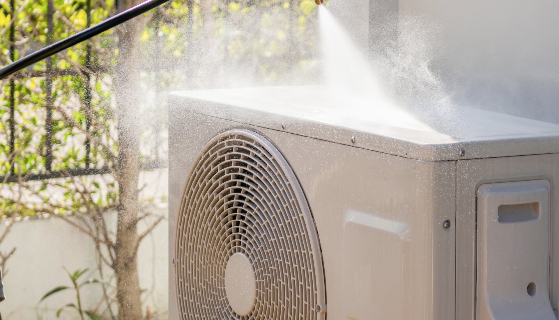 Technician cleaning dust from the coil of an outdoor air conditioner