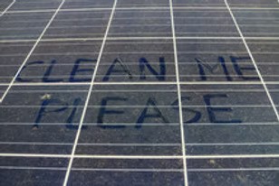 Dusty solar panels with the words CLEAN ME PLEASE written in the dust